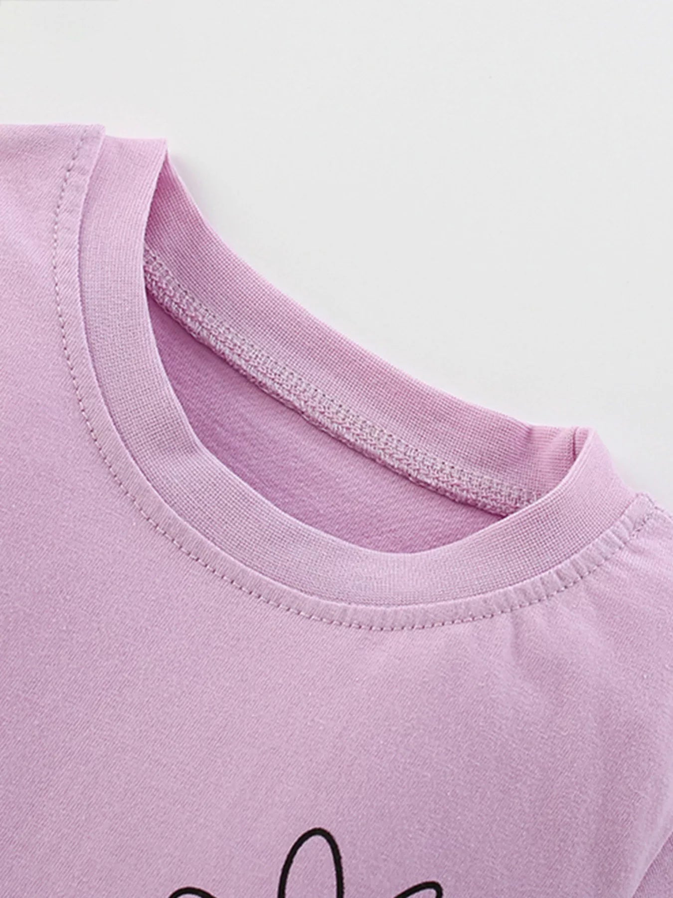 Close-up of a pink t-shirt with a brand logo on a white background