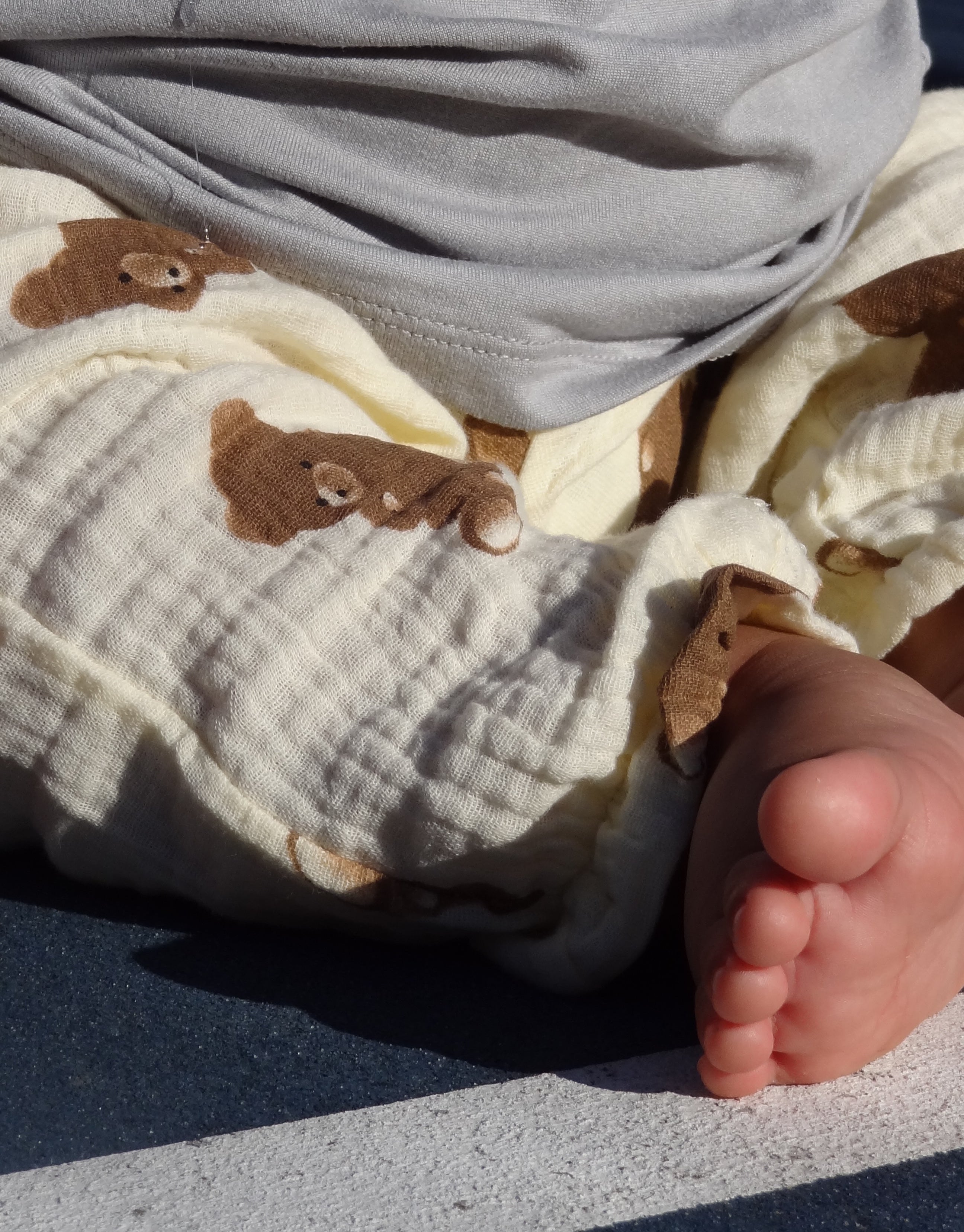 Close-up of a child's foot with a blanket featuring teddy bear patterns.