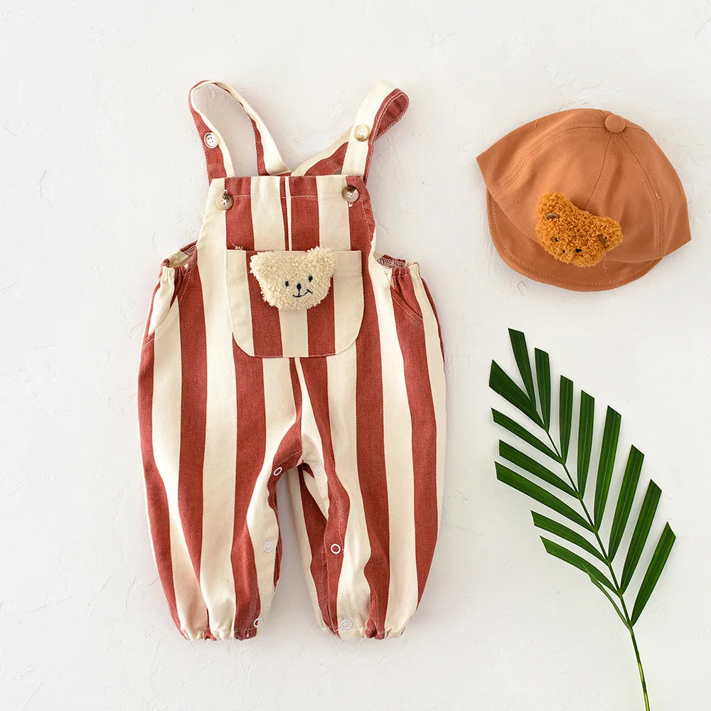 Striped overalls with teddy bear pocket and matching cap on a white background