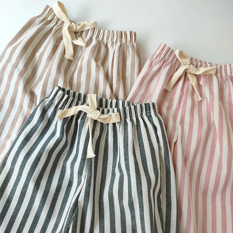 Three pairs of striped pants with ribbon ties on a white background