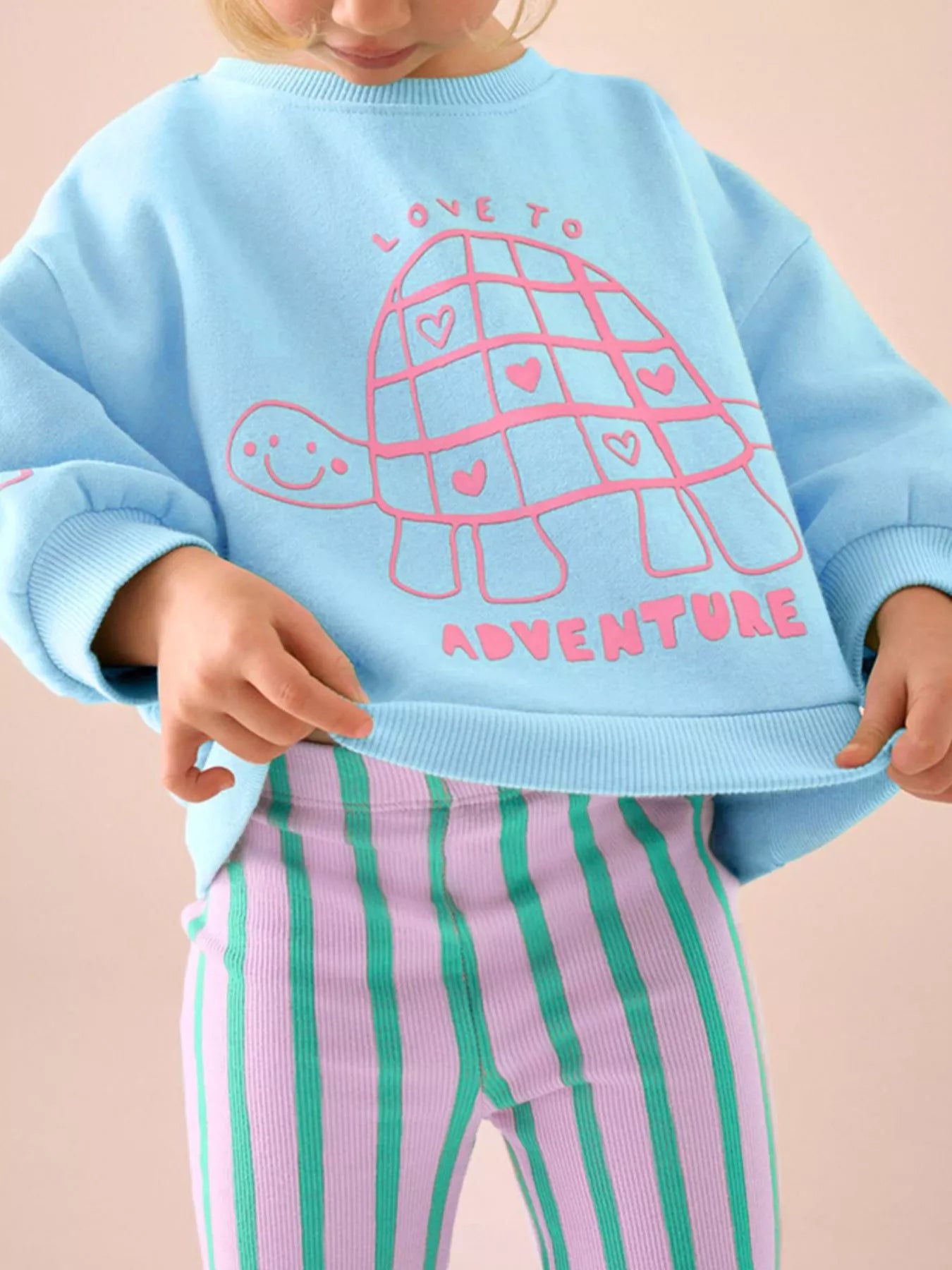 Girl holding Turtle Sweater and Stripped Pants 