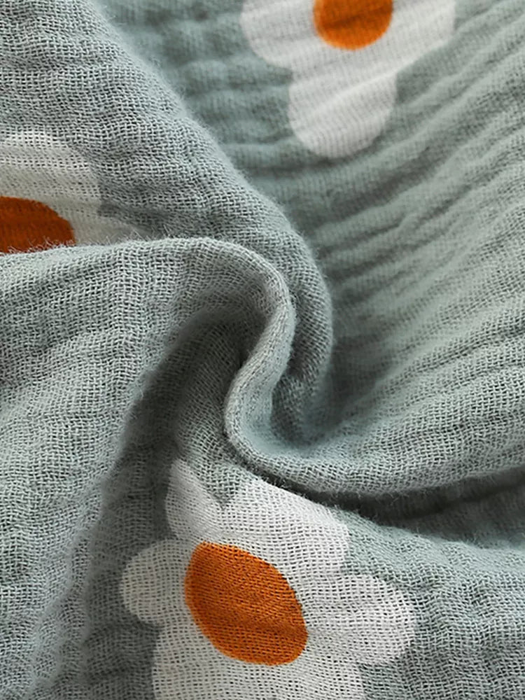Close-up of a fabric with floral patterns featuring orange centers and white petals.