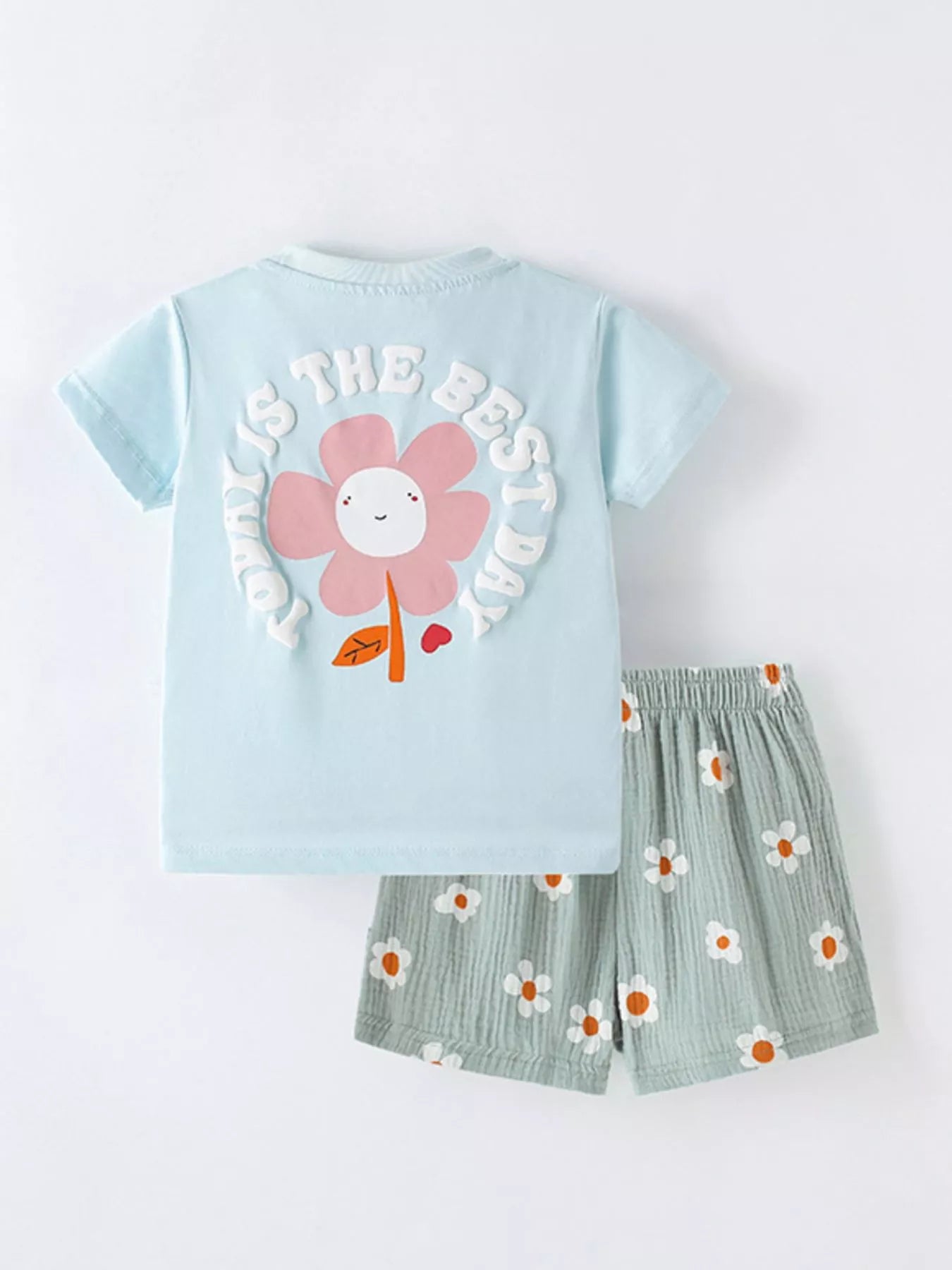 Children's outfit with light blue shirt and green shorts on a white background