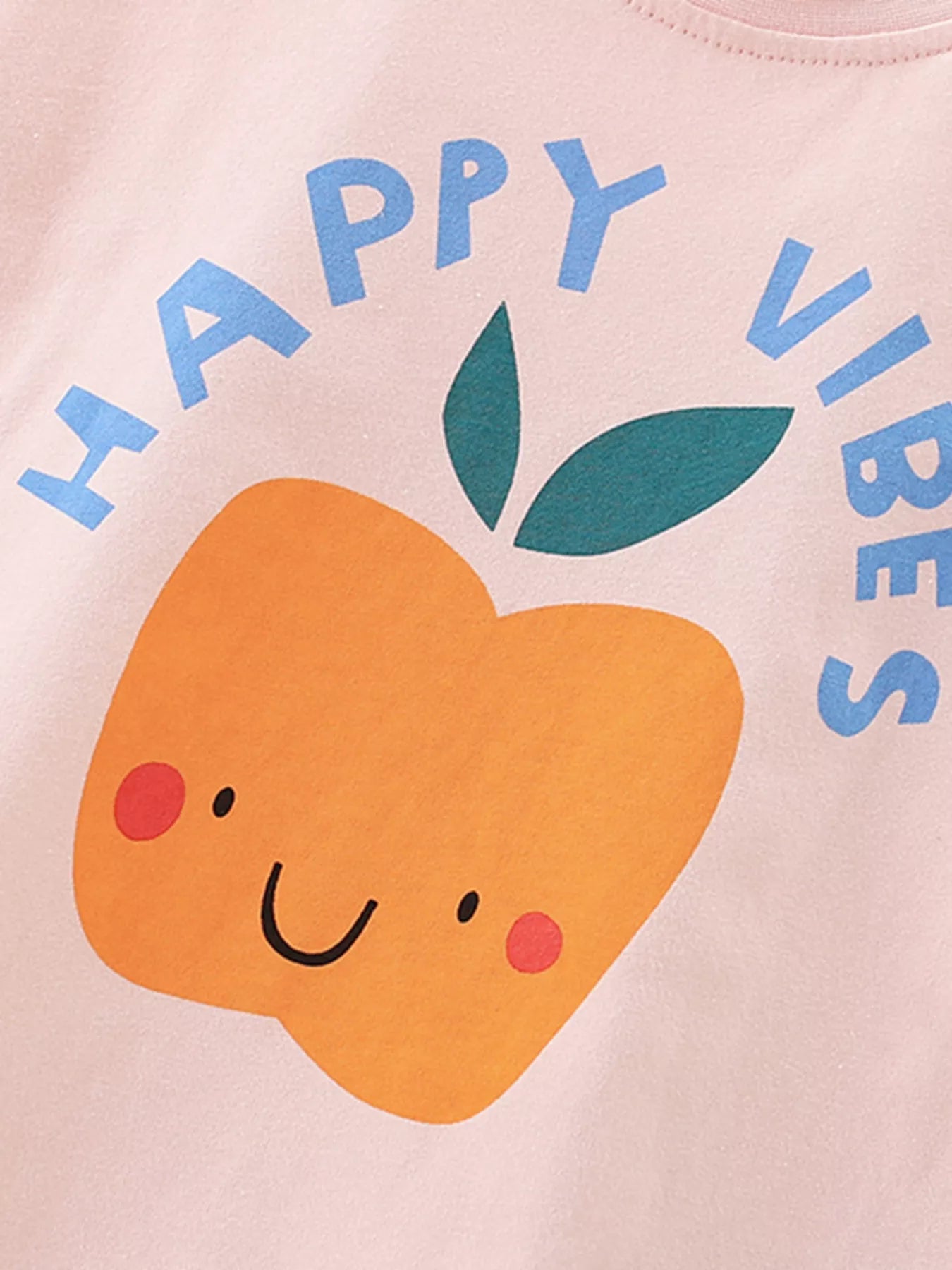 Pink shirt with a smiley peach and 'Happy Vibes' text on a light pink background