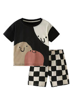 Children's outfit with a black and white shirt and checkered shorts on a light gray background