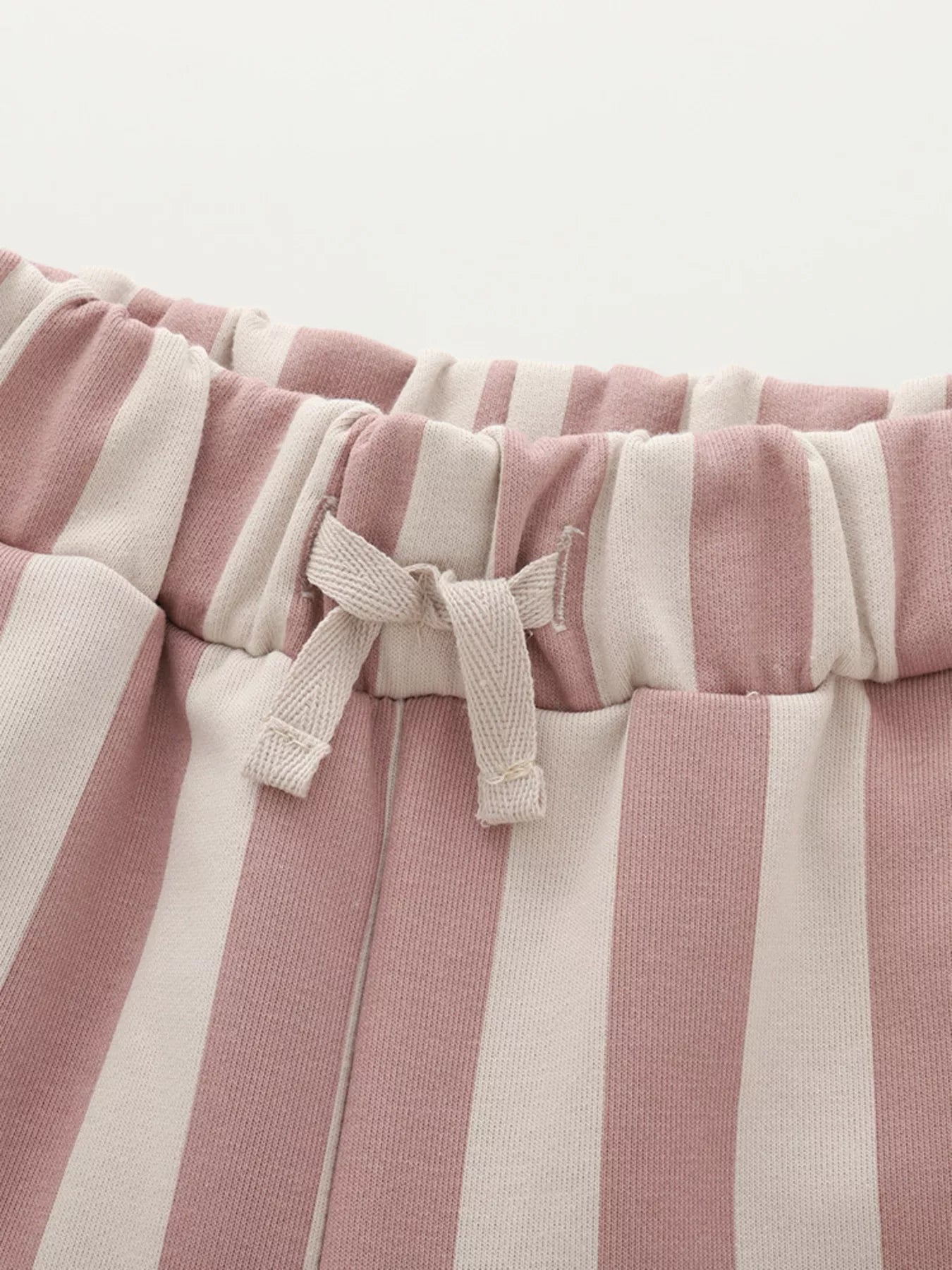 Close-up of pink and white striped pants with drawstring on a light gray background
